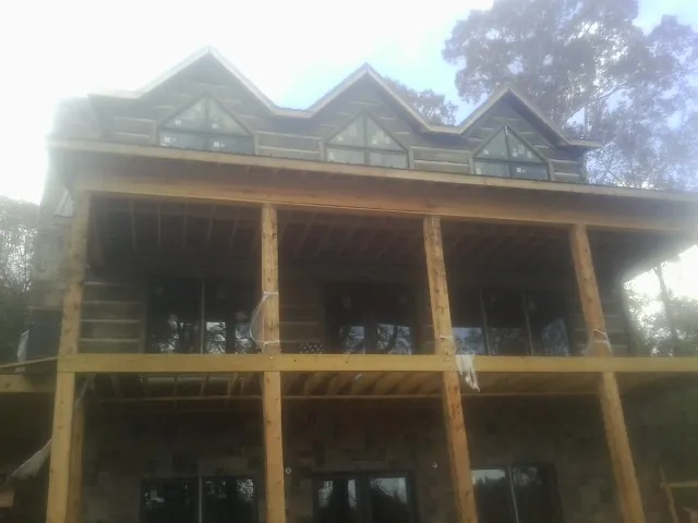 Dormers and porch framing on a large log home under construction — Roof Coating work by our crew in Homeland