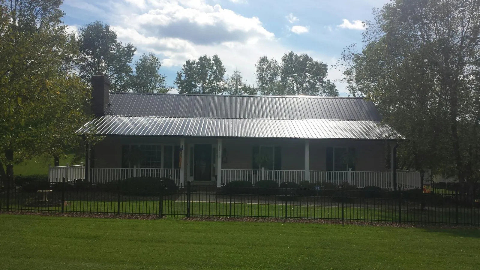Gray metal roof on a brick ranch with a full width front porch — Gutter Guard Installation work by our crew in Homeland