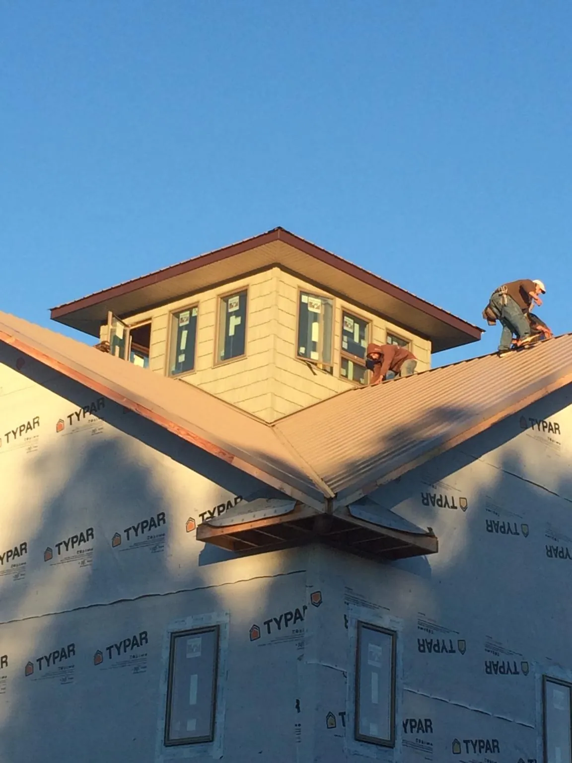 Roofers working around a rooftop cupola on a new metal roof at sunset — Roof Waterproofing in Homeland by Roofing Brothers